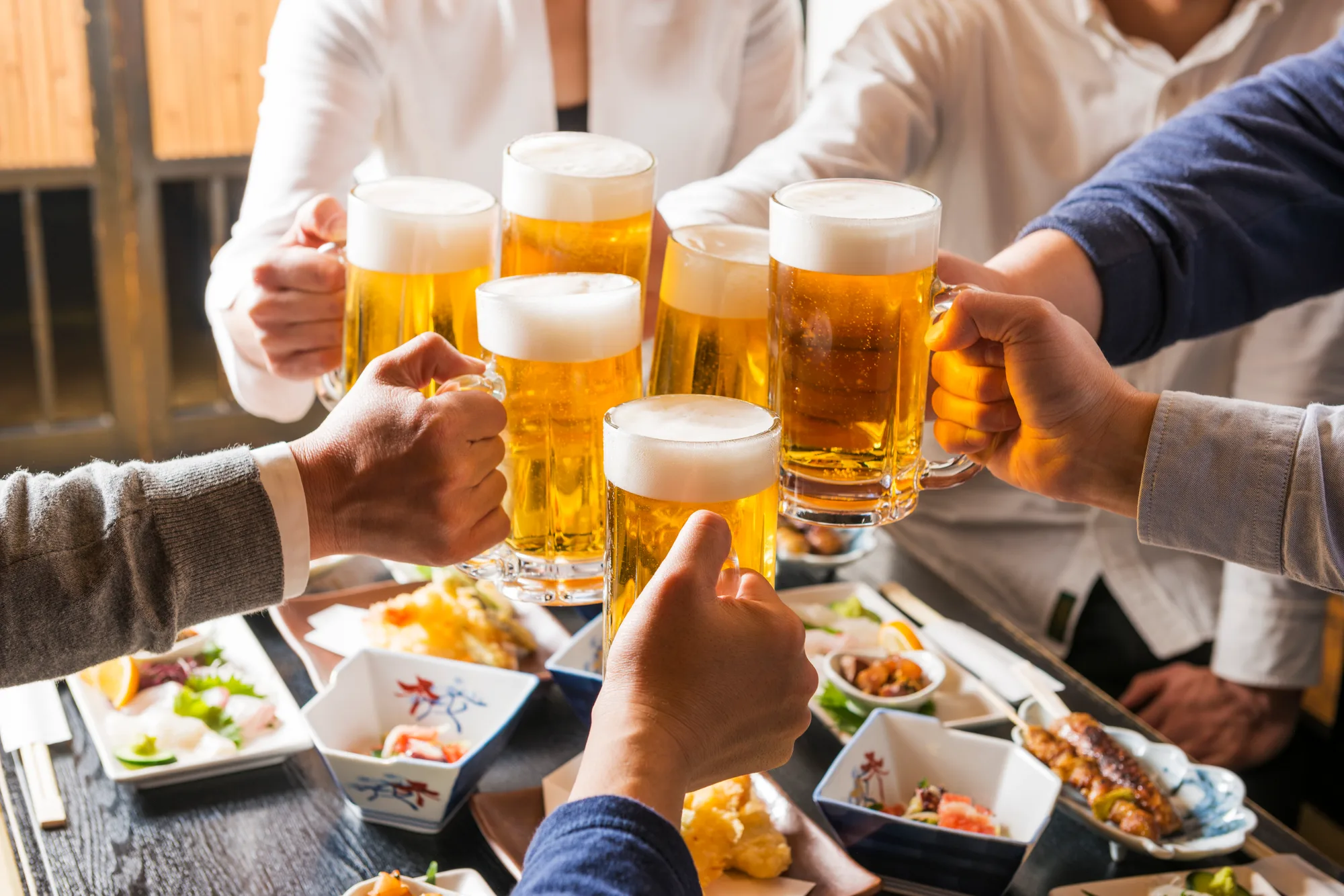 料理を囲みビールジョッキで乾杯する人々