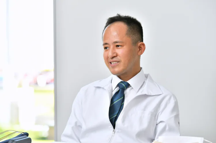 白衣姿で椅子に座りインタビューに答える西尾永司先生