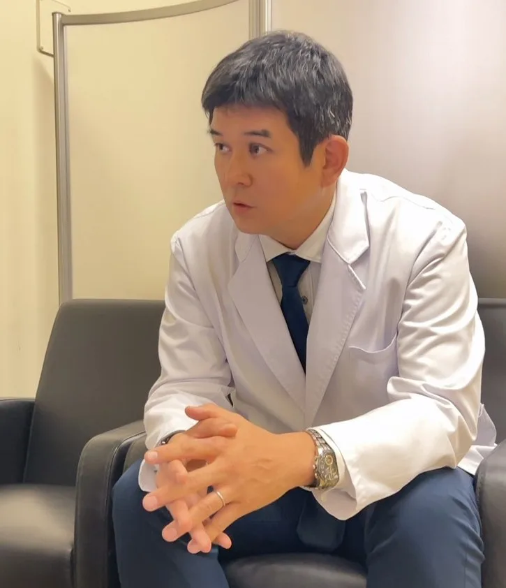 白衣姿でソファに座りインタビューに答える野上達也先生